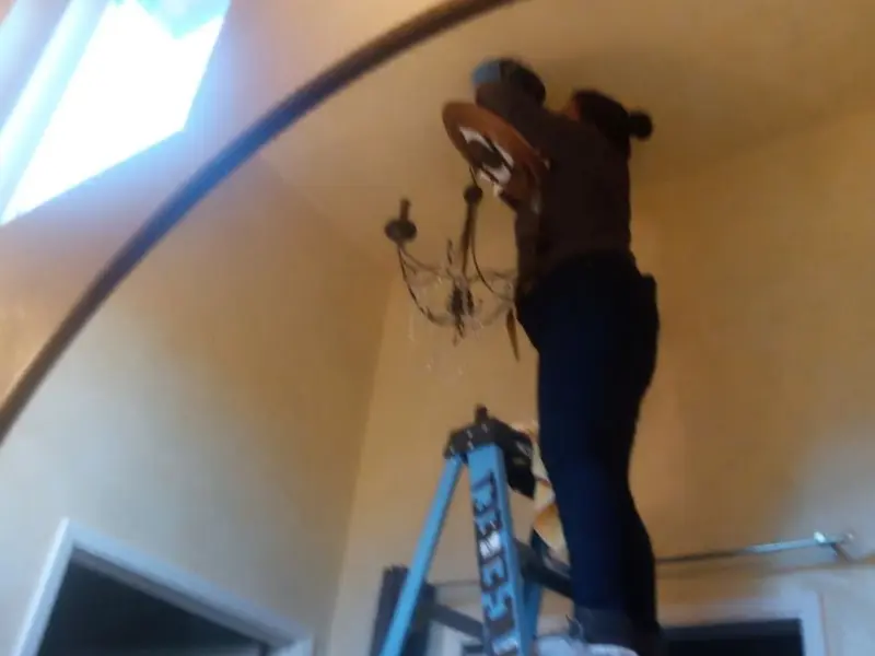 Electrician installing a chandelier in a Murray residence